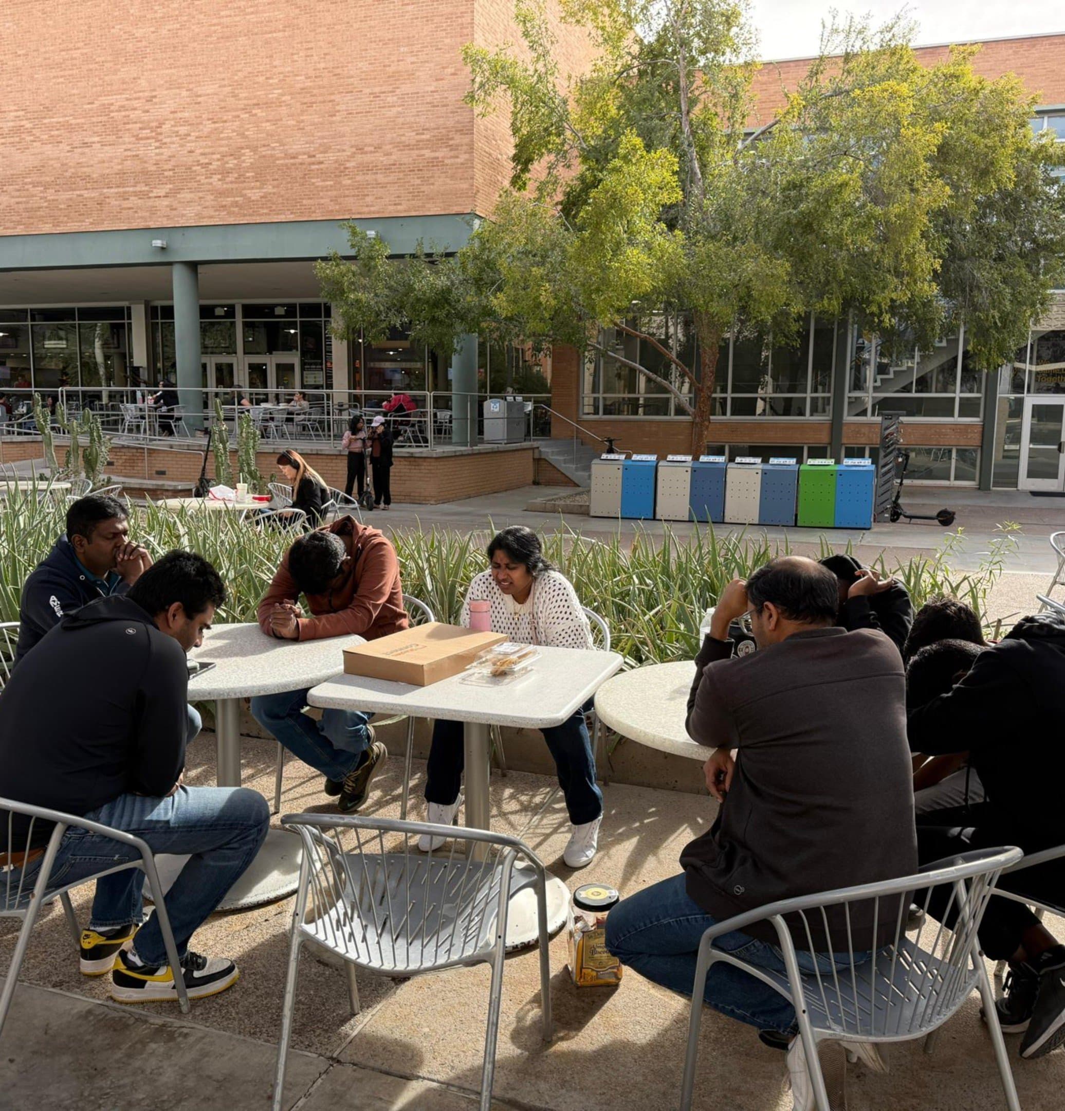 The team praying together on the ASU campus in 2025